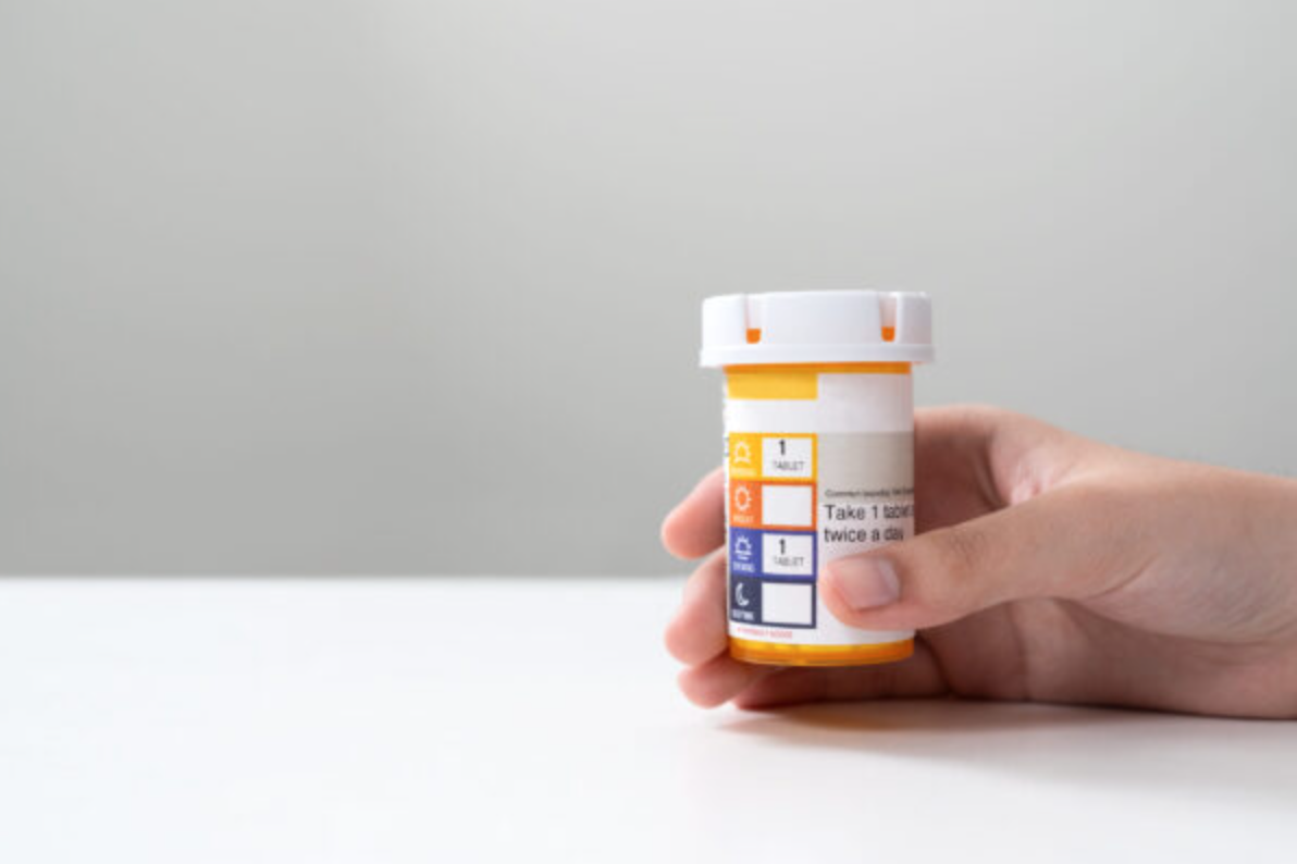 Hand hold an orange color pill bottle, concept for healthcare, medicine, pharmacy and prescription